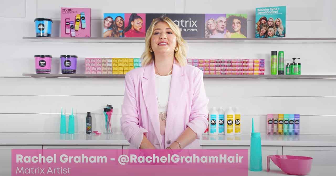Rachel Graham, a Matrix Artist, stands in a salon with shelves of Matrix hair products and tools in the background.